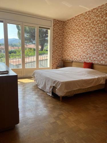 a bedroom with a bed and a large window at Au calme entre mer et montagne in Prades