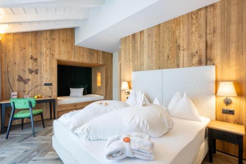 a bedroom with a bed with white pillows at Mirabell Dolomites Hotel - Luxury Ayurveda & Spa in Valdaora