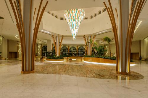 a lobby with a chandelier and palm trees at Cleopatra Sidi Heneish in Marsa Matruh
