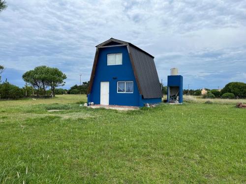 a blue house in a field of grass at Alquiler en Chapadmalal en el barrio "El Marquesado" in San Eduardo del Mar