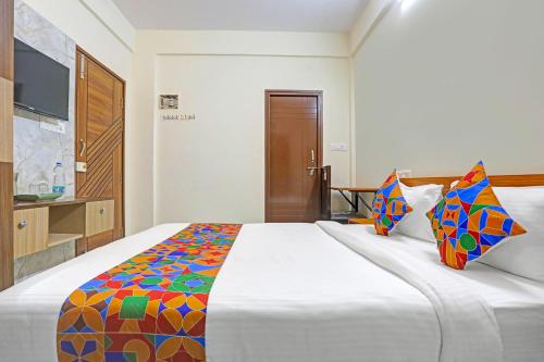 a bedroom with a large white bed with colorful pillows at FabHotel Tarini Comforts - Marathahalli in Bengaluru