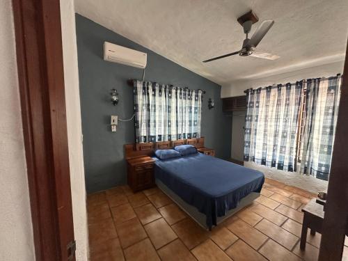 a bedroom with a bed with blue sheets and windows at The White House at Beach in Lo de Marcos