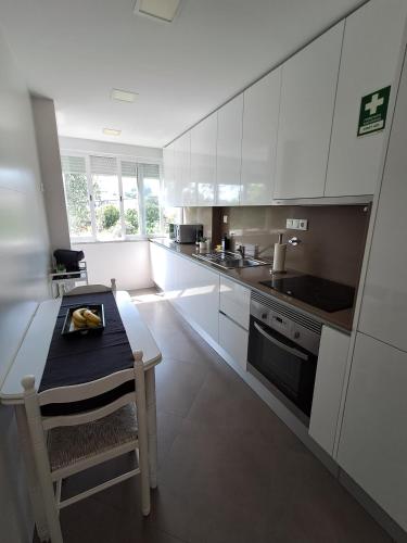 a kitchen with white cabinets and a table and a chair at Sweet Living Lisboa in Lisbon