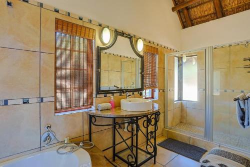 a bathroom with a tub and a sink and a shower at Stunning Bushveld Villa 84 in Warmbaths