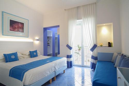 a blue and white bedroom with a bed and a couch at Hotel Aurora in Sperlonga
