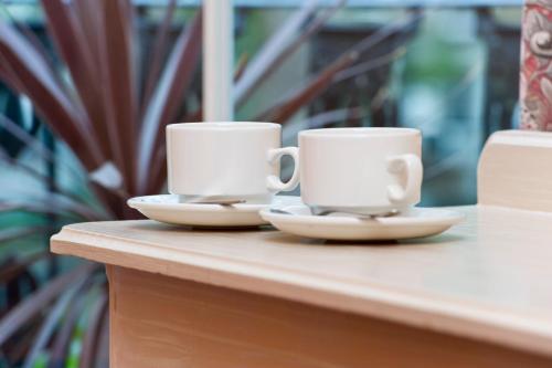 two white coffee cups sitting on a table at Macdonald Hotel in London