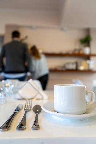 a white coffee cup on a table with silverware at Hotel PUERTO A in Gualeguaychú