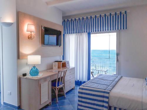 a bedroom with a desk and a bed and a window at Hotel Aurora in Sperlonga