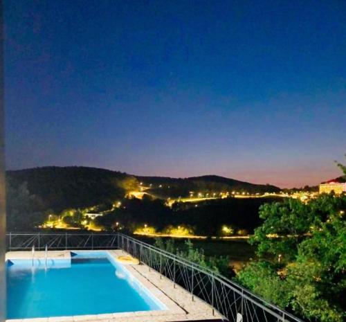 a swimming pool with a view of a city at night at Just Joy Apartman in Vrdnik