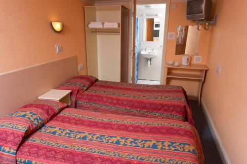 a hotel room with two beds and a sink at Macdonald Hotel in London
