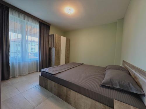 a bedroom with a bed and a large window at Seagull Apartments in Byala