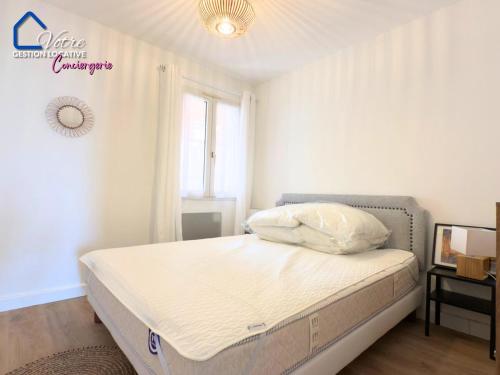 une chambre avec un lit avec des draps blancs et une fenêtre dans l'établissement Casa Luna, à Collioure