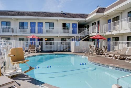 a large swimming pool in a hotel with chairs and umbrellas at Motel 6-Salem, OR in Salem