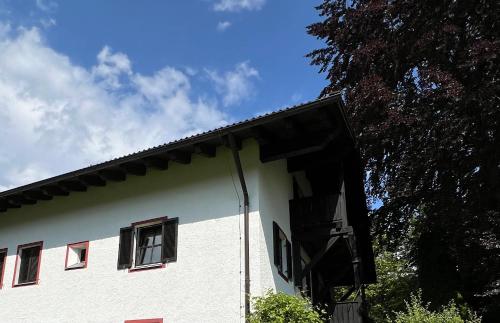 a white building with red windows and a tree at Ferienwohnung Am Kurpark in Aschau im Chiemgau
