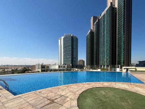 a swimming pool on the roof of a building with tall buildings at Reem Island, Unique furnished one bedroom with amazing seaview in Abu Dhabi