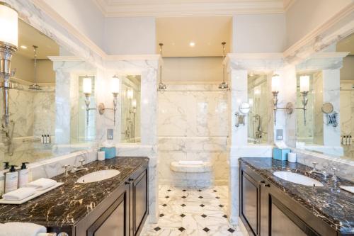 a bathroom with two sinks and two mirrors at Lucknam Park Hotel in Chippenham