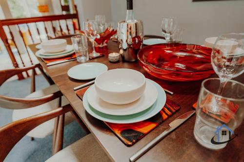 a wooden table with plates and glasses on it at Unique Boathouse, detached free parking x4 cars in Kingston upon Thames