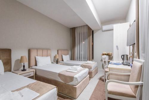 a hotel room with two beds and a desk at Golden Horizon Hotel in Tashkent