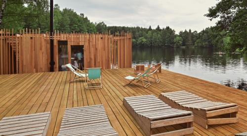 a wooden dock with two chairs and chairs on a lake at Hotel Kouty - Lesní Apartmány in Ledeč nad Sázavou