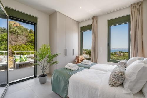 a bedroom with two beds and a large window at Villa Meraki in Stalos
