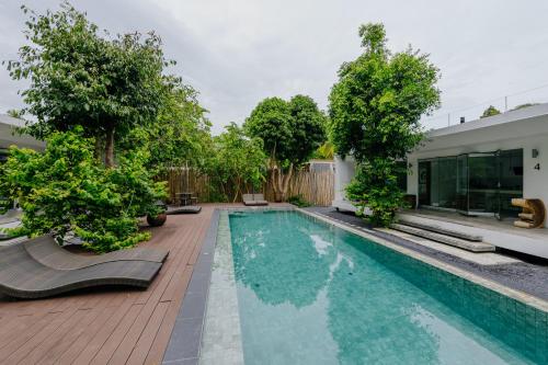 a swimming pool with trees and a house at KPG Suite Dream in Ban Nua