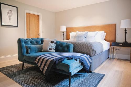 a bedroom with a bed and a blue couch at Lucknam Park Hotel in Chippenham