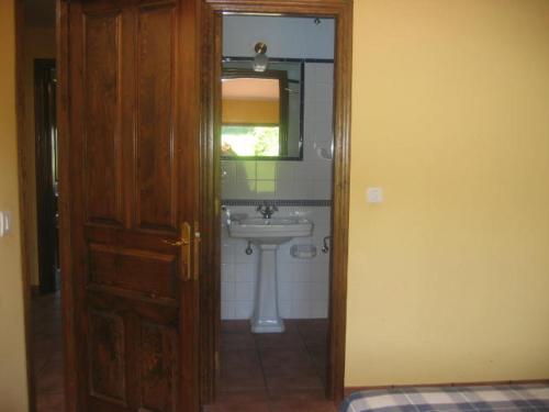 ein Badezimmer mit Waschbecken, Spiegel und Tür in der Unterkunft La Busta in Villaviciosa