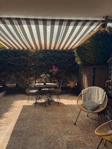d'une terrasse avec une table et des chaises sous un auvent. dans l'établissement Charmant studio avec piscine et jardin, à Cannes