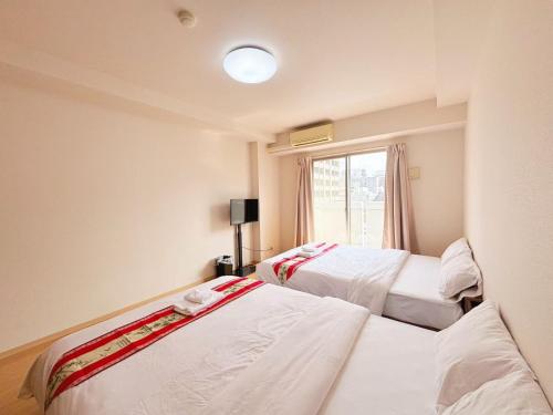 two beds in a room with a window at ARSTAy池袋62 in Tokyo