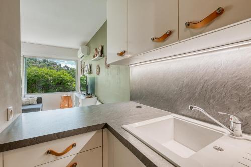 une cuisine avec un évier blanc et une fenêtre dans l'établissement Appartement La Fossette , 4 personnes, 5mn de la plage, WIFI, climatisation, parking, terrasse sans vis-à-vis, au Lavandou