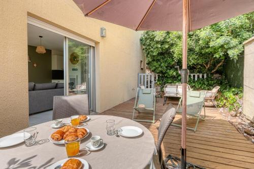 - une table avec de la nourriture et un parapluie dans l'établissement Appartement La Fossette , 4 personnes, 5mn de la plage, WIFI, climatisation, parking, terrasse sans vis-à-vis, au Lavandou