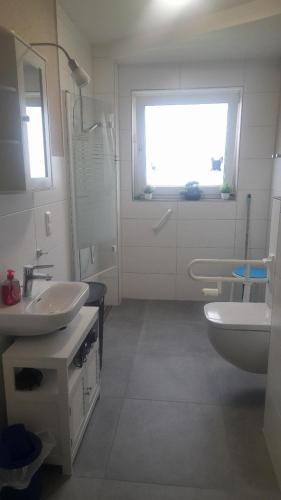 a bathroom with two sinks and a toilet and a window at Heideglück, Ferienwohnung in Schneverdingen