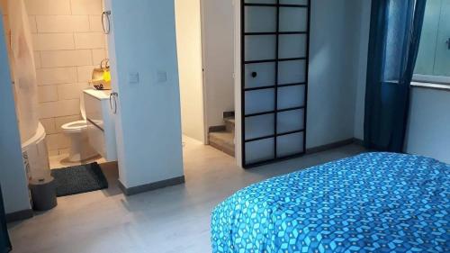 a bedroom with a blue bed and a bathroom at Maison de Village in Canet d'Aude