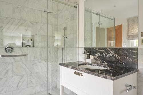 a bathroom with a sink and a glass shower at Lucknam Park Hotel in Chippenham