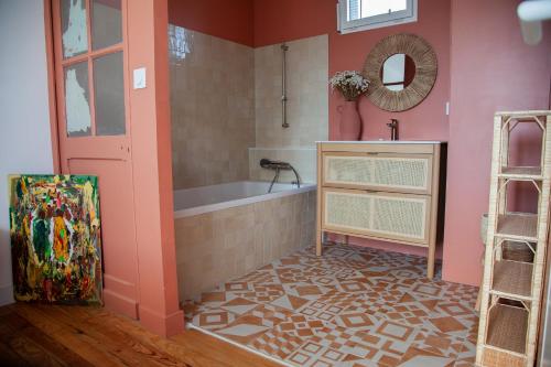 - une salle de bains rose avec une baignoire et un miroir dans l'établissement Villa centre-ville, proche plage, au Pouliguen