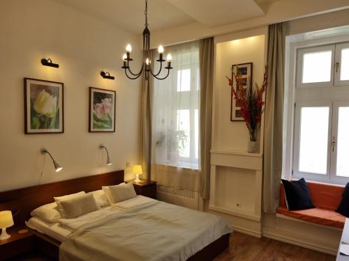a bedroom with a bed and two windows and a chandelier at Connection Guesthouse in Budapest