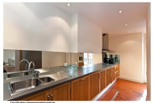 une cuisine avec des placards en bois et un évier en acier inoxydable dans l'établissement REF 35 - Cannes Center - Duplex apartment for rent, à Cannes