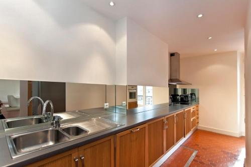 une cuisine avec des placards en bois et un évier en acier inoxydable dans l'établissement REF 35 - Cannes Center - Duplex apartment for rent, à Cannes