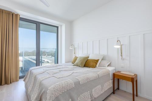 a white bedroom with a large bed and a large window at Central Heaven in Ostend