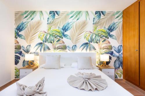a bedroom with a white bed with a tropical wallpaper at Best duplex FREE WIFI in Playa Paraiso