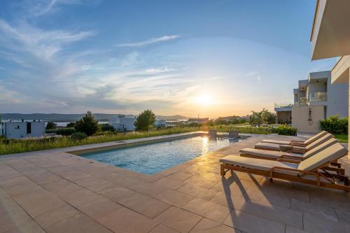 einen Pool mit Liegestühlen neben einem Gebäude in der Unterkunft Villa Belvedere 1 ZadarVillas in Sveti Filip i Jakov
