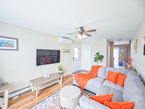 a living room with a gray couch and orange pillows at Tranquil Riverside Abode in Cornwall
