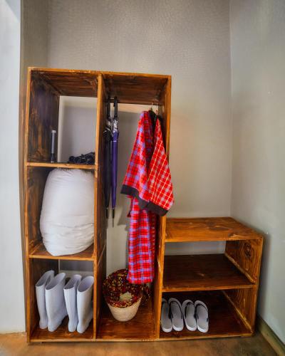 a wooden book shelf with shoes and a towel at Pamoja Farm Villas in Karatu