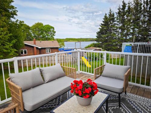 a porch with two chairs and a table with flowers at Tranquil Riverside Abode in Cornwall