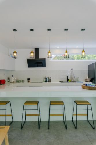 a kitchen with three bar stools at a counter at KPG Suite Dream in Ban Nua