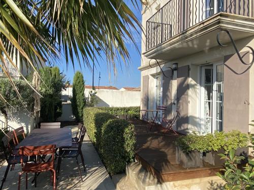 un patio avec une table et des chaises à côté d'un bâtiment dans l'établissement La Batelière, entre mer, Camargue et Canaux, à Aigues-Mortes