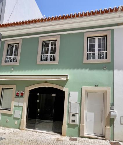 a green building with a doorway and two windows at Oeste Garden Suites in Caldas da Rainha