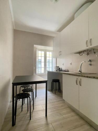 a kitchen with a black table and some chairs at Oeste Garden Suites in Caldas da Rainha