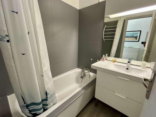 une salle de bain avec un lavabo, une baignoire et un miroir dans l'établissement Appartement avec terrasse, vue sur l'Océan et parking à Royan - FR-1-494-33, à Royan