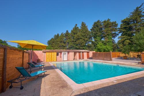 une piscine avec deux chaises et un parasol dans l'établissement Maison provençale avec jardin, à Velleron